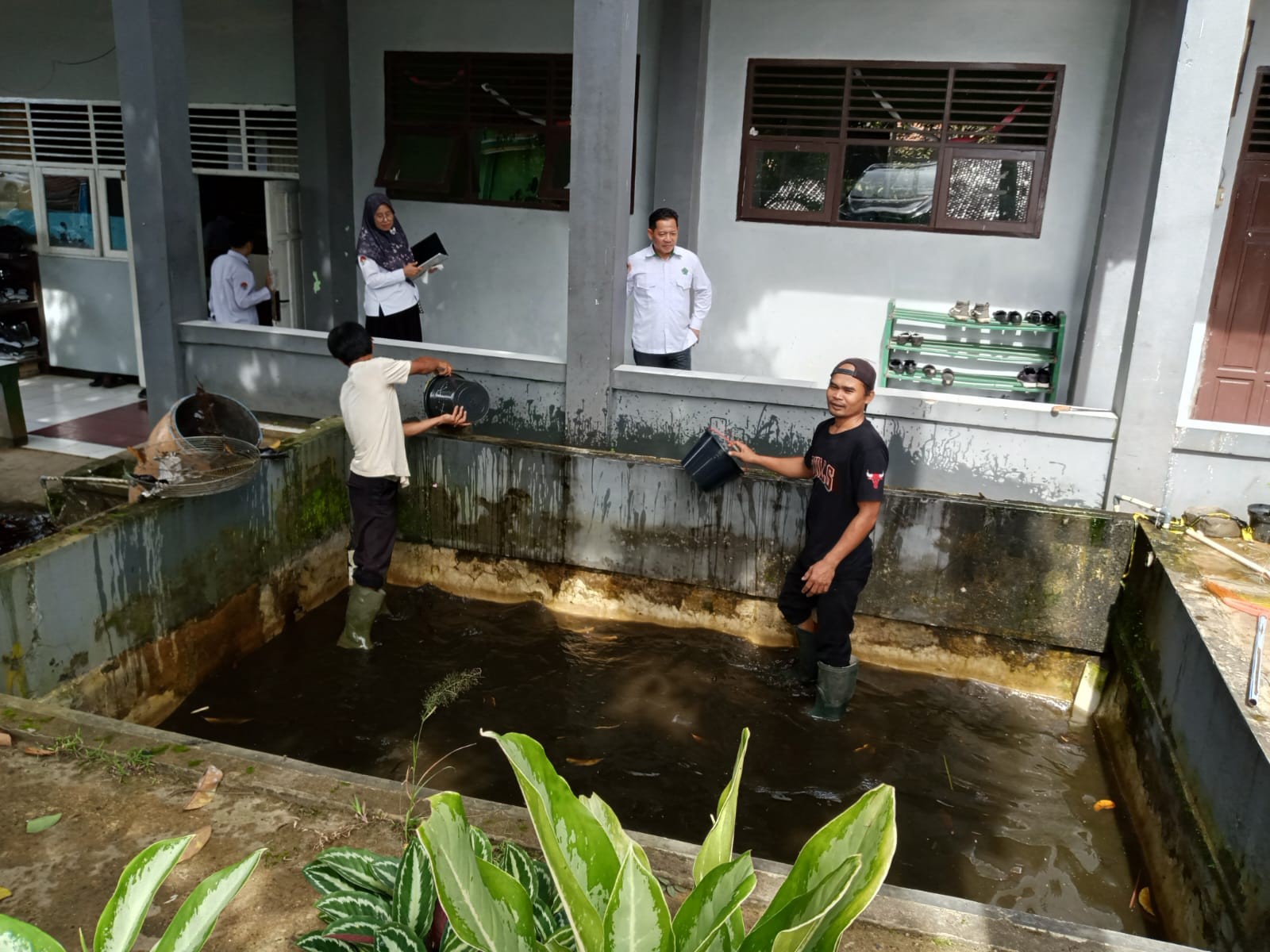 Tim Kebersihan MAN 2 Bogor Menguras Kolam Ikan