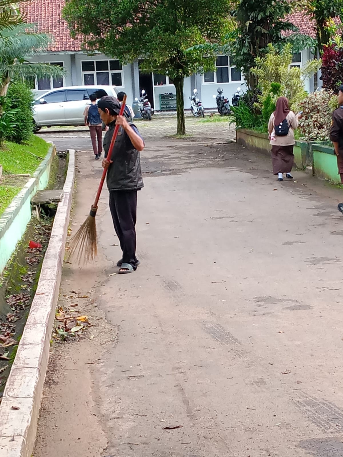 Staff Kebersihan Membersihkan Jalur Utama Madrasah Setiap Pagi
